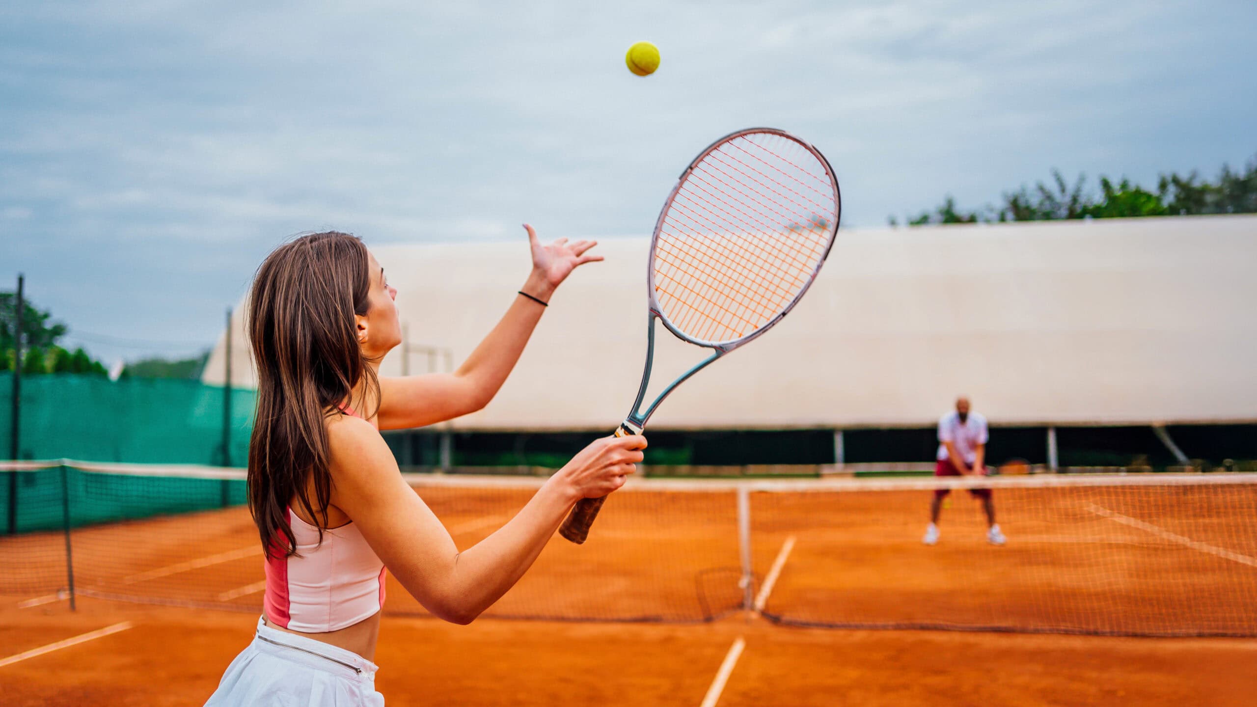 Tennis player prepares to serve on a clay court.
