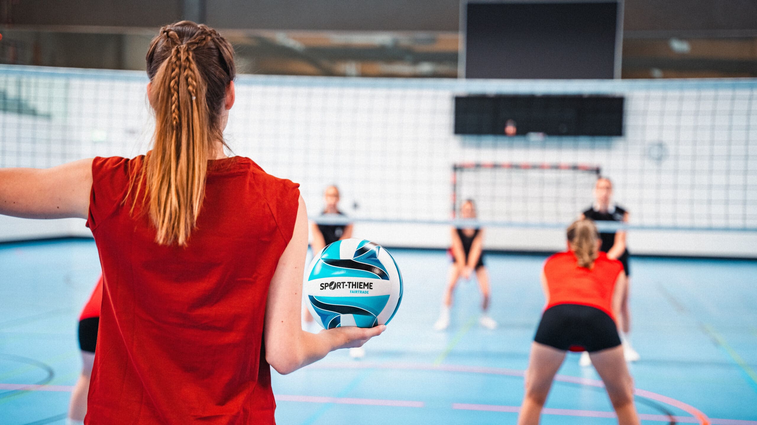 Volleyball player ready to serve in an indoor court.