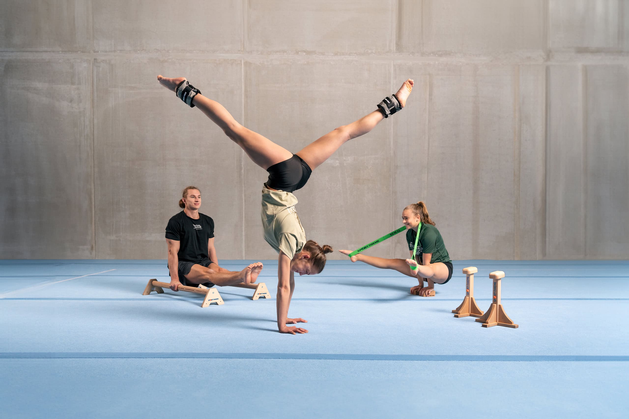 Turnerinnen und Turner des „Feuerwerk der Turnkunst“ beim Training mit Sport-Thieme Equipment auf einer blauen Bodenfläche.