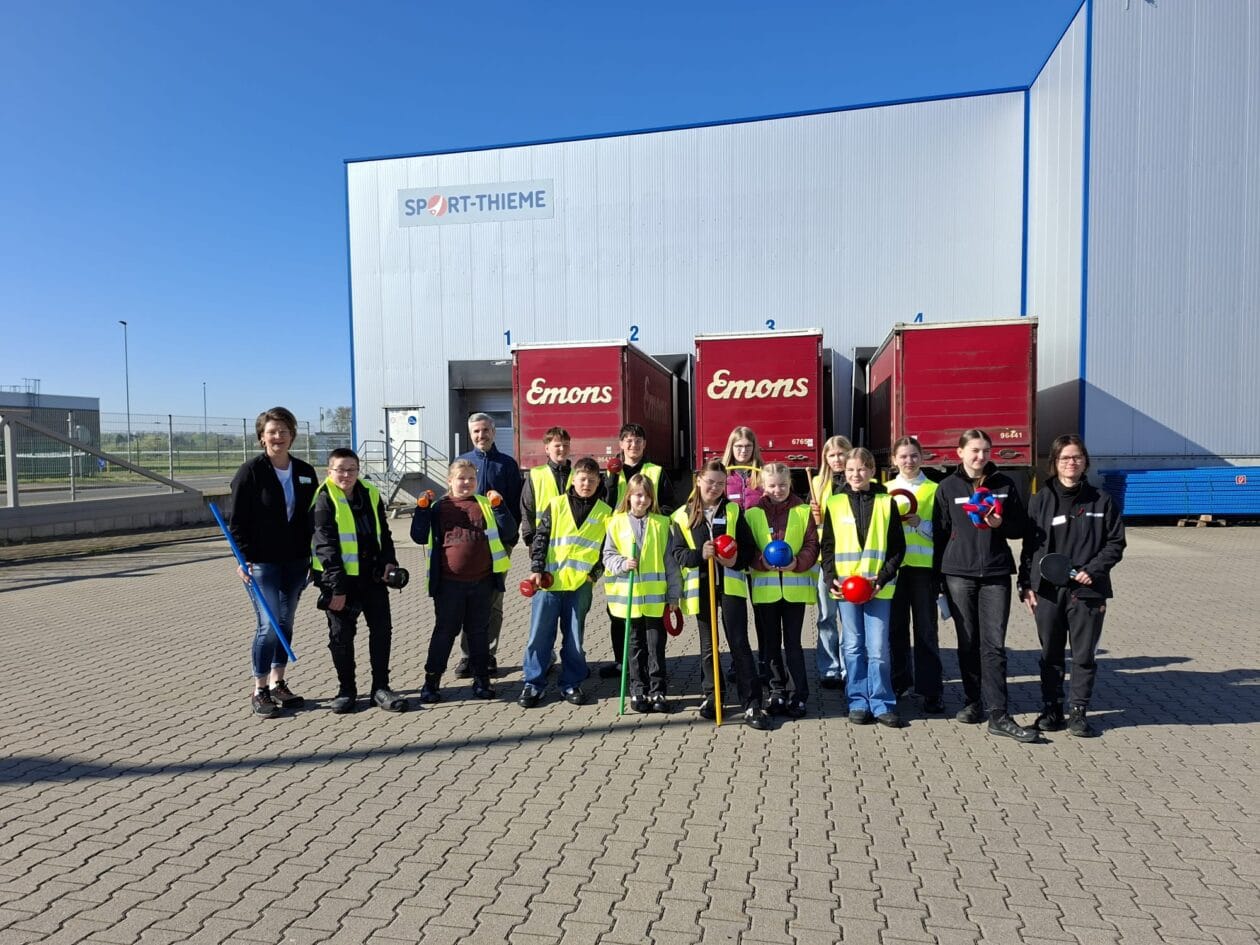 Gruppenfoto von Schüler:innen und Betreuenden vor dem Logistikzentrum von Sport-Thieme.